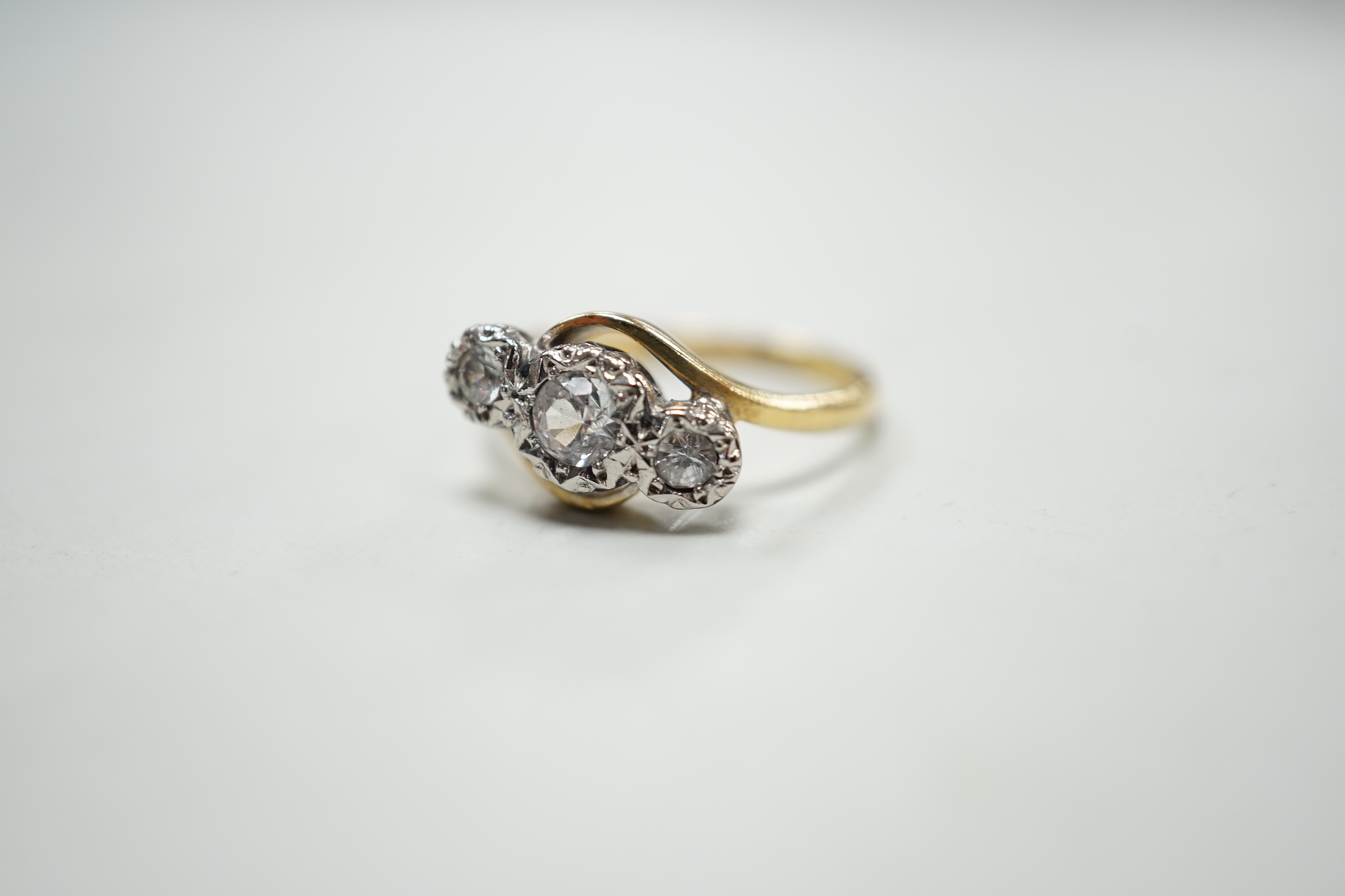 An 18ct and illusion set three stone diamond crossover ring, size I, gross weight 2.5 grams.